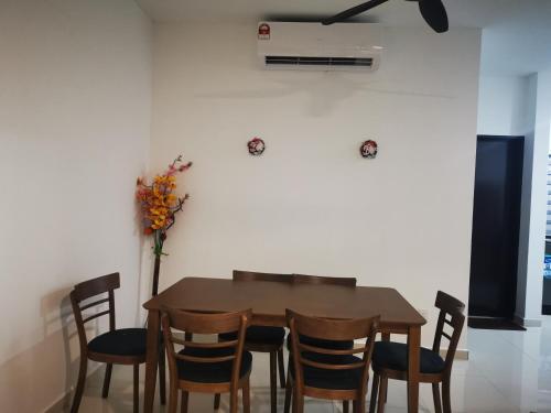 a dining room table with chairs and a vase with flowers at 48 悠之处NO . 48, PERSIARAN ALAM IMPIAN 3 VILLA RIADAH ALAM IMPIAN PANGKOR, 32300 PANGKOR , PERAK. in Pangkor