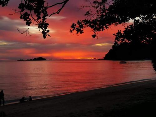 a sunset over the water with people on the beach at 48 悠之处NO . 48, PERSIARAN ALAM IMPIAN 3 VILLA RIADAH ALAM IMPIAN PANGKOR, 32300 PANGKOR , PERAK. in Pangkor