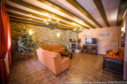 a living room with a couch and a christmas tree at Casa Rural Castillo Diempures in Cantalojas