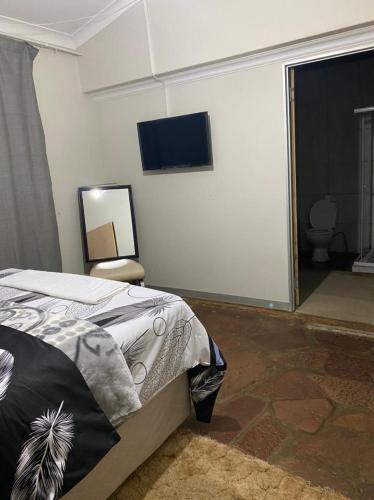 a bedroom with a bed and a flat screen tv at 26 Zea avenue Arcon Park Guest House in Vereeniging