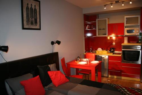 un salon avec un canapé et une cuisine avec des placards rouges dans l'établissement Savinac apartman u srcu Beograda, Trg Slavija, à Belgrade
