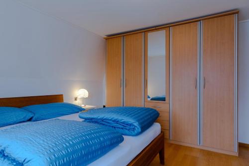 a bedroom with a bed with blue sheets and a cabinet at Blattenheimat - im traditionellen Appenzeller Haus in Appenzell