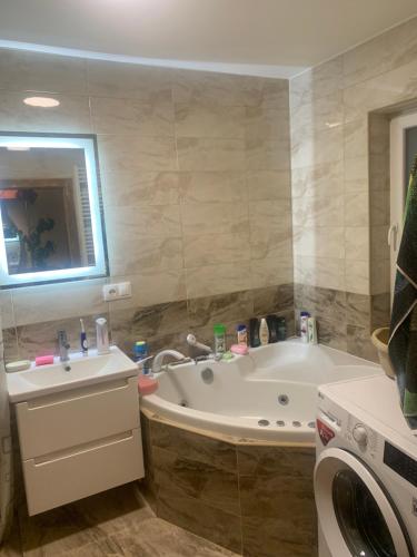 a bathroom with a tub and a sink and a washing machine at Котедж in Podobovets