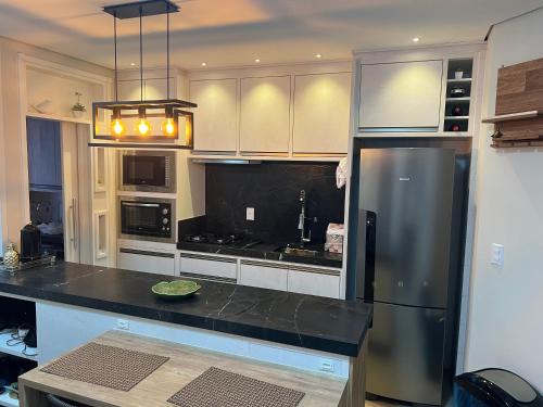 Il comprend une cuisine équipée d'un comptoir noir et d'un réfrigérateur. dans l'établissement Studio 703 - Ravenna Residence, à Itajaí