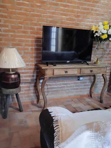 a television on a wooden table with a lamp at Casa/chalé Furnas - Capitólio MG in São José da Barra