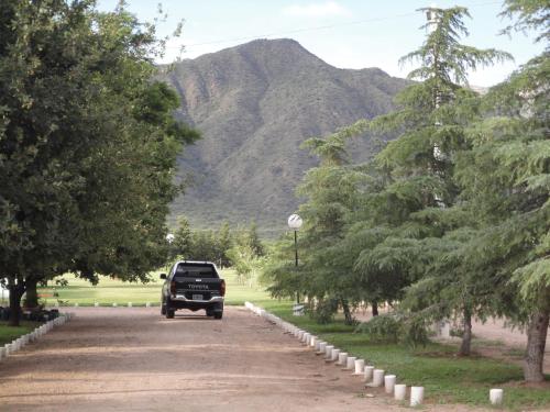 a truck driving down a dirt road with a mountain at Hotel Lujan in Luján
