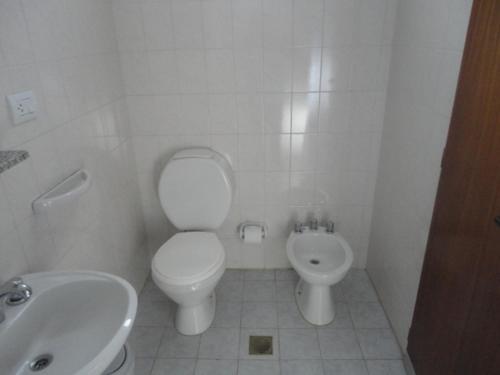 a white bathroom with a toilet and a sink at Hotel Lujan in Luján