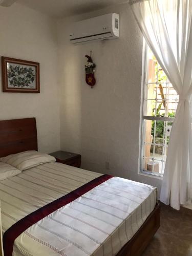 a bedroom with a bed and a window at Casa Nona Rosa in Cancún