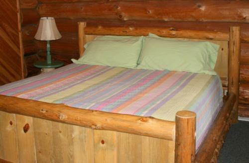 uma cama num chalé de madeira com uma estrutura de cama de madeira em Cedar Mountain Farm Bed and Breakfast LLC em Athol