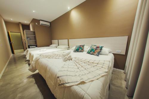 una camera d'albergo con due letti con lenzuola bianche di Paraiso Natural Apart Hotel Iguazu a Puerto Iguazú