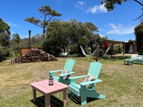 two chairs and a table in a yard at Los Pecados de la Viuda in Punta Del Diablo