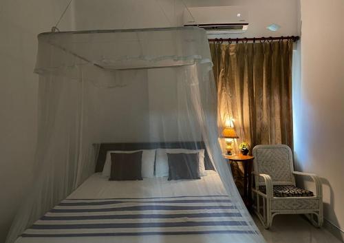 a bedroom with a canopy bed and a chair at Number 01 by Taprobane in Negombo