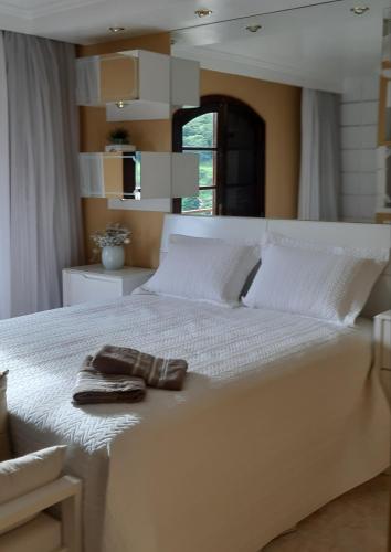 Una cama blanca con un par de zapatos. en Apartamento completo, en São Lourenço