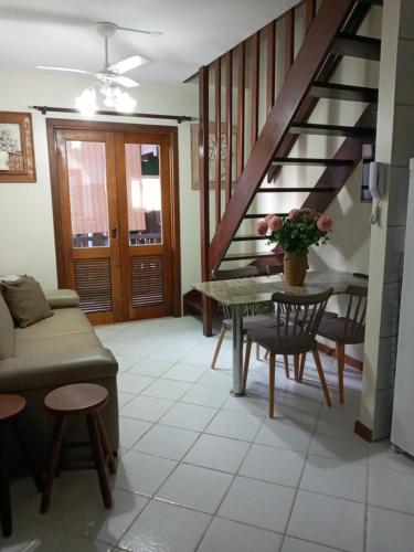 een woonkamer met een trap en een tafel en stoelen bij Duplex em Praia do Forte a 50m da vila in Mata de Sao Joao