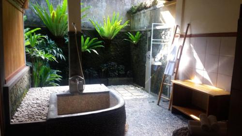 uma casa de banho com um chuveiro e uma banheira com plantas em Nefatari Exclusive Villas em Ubud