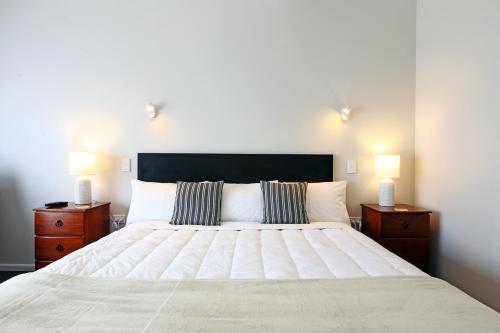 1 dormitorio con 1 cama blanca grande y 2 mesitas de noche en 289 Midway Motel, en Oamaru