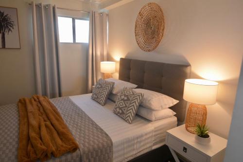 una camera da letto con un letto con cuscini e due lampade di City Stadium One Bedroom Luxe a Townsville