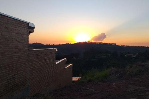 a sunset with the sun setting on a mountain at La Villa Chalés in Serra Negra