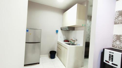 a small kitchen with a refrigerator and a sink at Kozy Room Sentul Tower Apartemen in Bogor