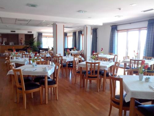 a dining room with white tables and wooden chairs at Hotel Mirafresno in Miranda do Douro