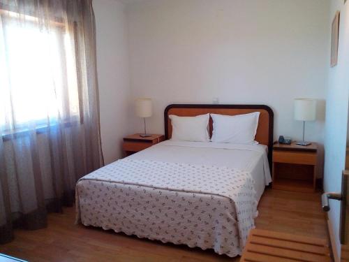 a bedroom with a large bed with two tables and a window at Hotel Mirafresno in Miranda do Douro