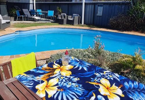 a blue and yellow blanket on a table next to a swimming pool at Avlon Gardens Motel in Ballina