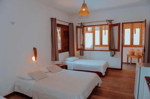 a bedroom with two beds and two windows at Vila Moana Jeri in Jericoacoara