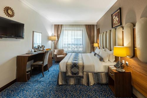 Grand Al Safi Hotel في المدينة المنورة: غرفة الفندق بسرير كبير ومكتب