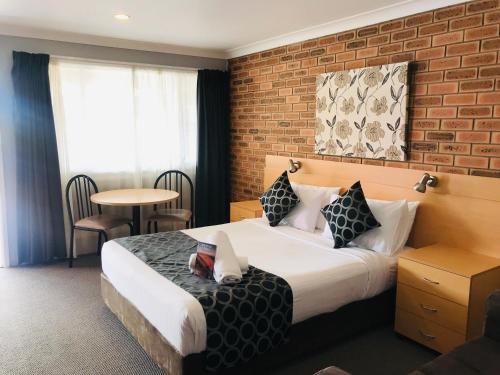 a hotel room with a bed and a brick wall at Jumbuck Motor Inn in Tenterfield