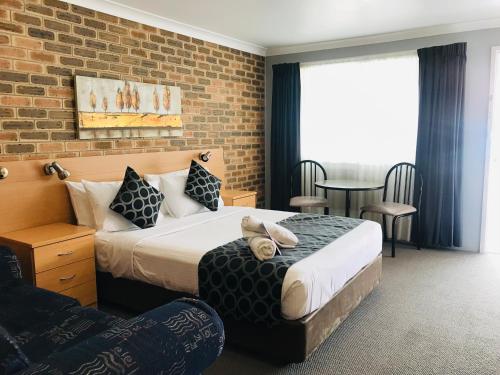 a hotel room with two beds and a brick wall at Jumbuck Motor Inn in Tenterfield