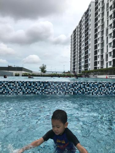 a young boy in the water in a swimming pool at Der’s Apartment in Bandar Penawar
