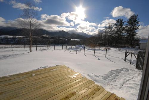 a snow covered yard with the sun in the sky at Tarochan House in Engaru