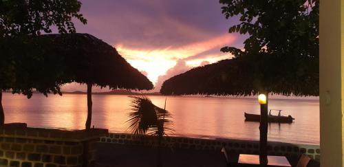 a sunset over a body of water with a boat at Anjiamarango Beach Resort in Nosy Be