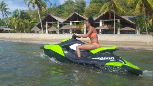 a woman riding on a jet ski in the water at Anjiamarango Beach Resort in Nosy Be