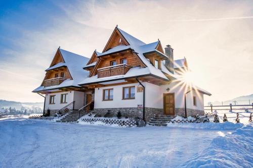ein schneebedecktes Haus, auf dem die Sonne scheint in der Unterkunft Apartamenty ROZETA Poronin in Poronin