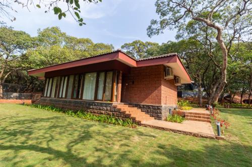 a small brick house in a grassy field at R R Heritage Resort Pure Vegetarian in Mahabaleshwar