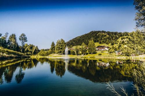 a lake with a waterfall and a house in the background at FOUR PEAKS Apartment in Flachau