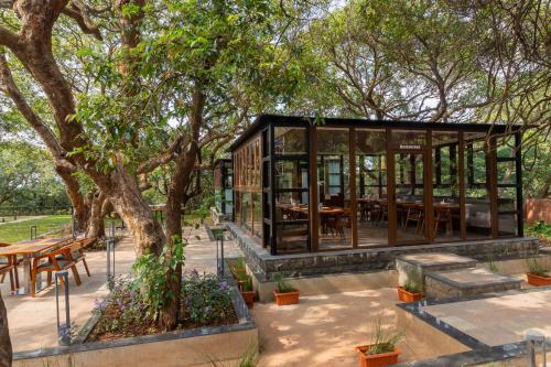 a glass pavilion in a park with tables and trees at R R Heritage Resort Pure Vegetarian in Mahabaleshwar