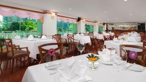 a dining room with white tables and chairs and windows at Hotel Sintra in Macau