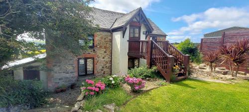 a brick house with a balcony and some flowers at Red Fox Barn in Perranporth