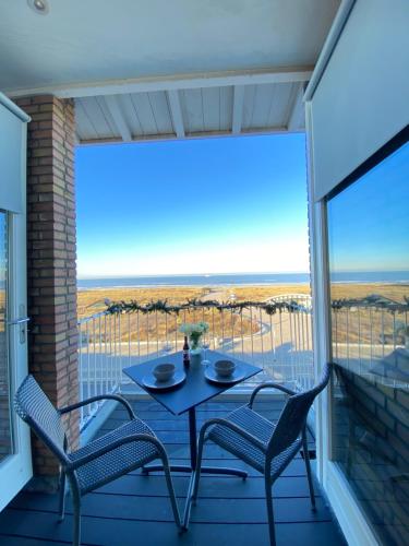 a patio with a table and chairs on a balcony at Eb en Vloed Katwijk in Katwijk