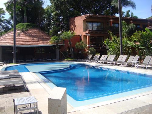 a large swimming pool with chairs and a house at Hosteria Las Quintas Hotel Restaurante Bar in Cuernavaca