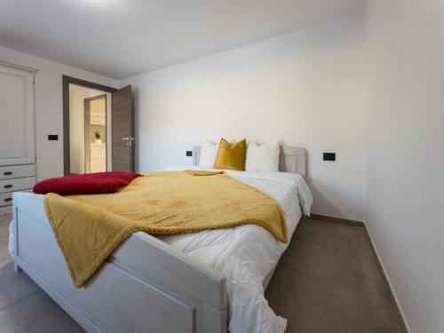 een witte slaapkamer met een bed met een gele deken erop bij La Maison de Papagran CIR Charvensod-0007 in Aosta
