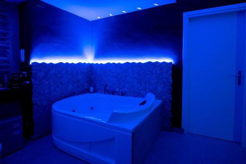 La salle de bains est pourvue d'une baignoire blanche et d'un éclairage bleu. dans l'établissement Le Dimore di Freya, à Catane
