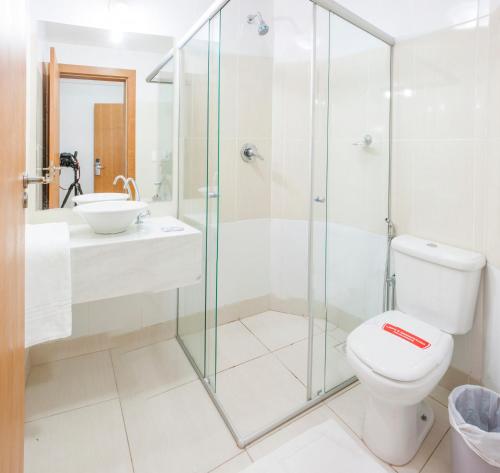 uma casa de banho com um chuveiro, um WC e um lavatório. em Hotel Abba Uno em Betim