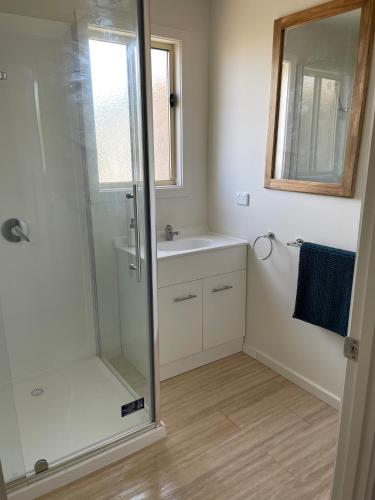 een badkamer met een douche, een wastafel en een spiegel bij Portland Bay Lodge, 2 Bedroom Apartments in Portland
