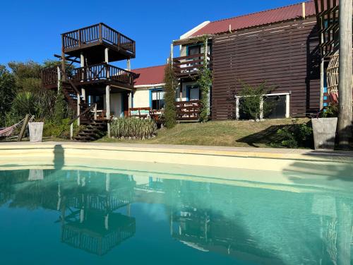 a house with a swimming pool in front of a house at Posada de la Viuda in Punta Del Diablo
