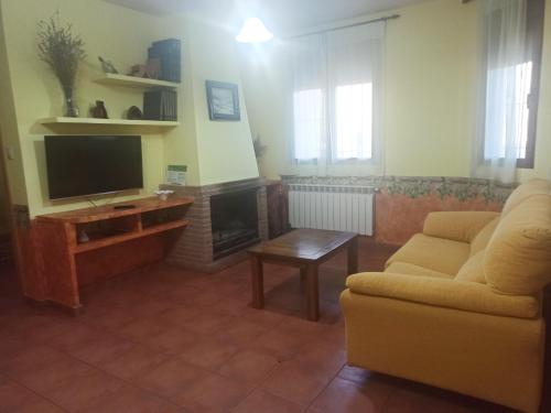 a living room with a couch and a television at Casas Rurales Montemayor in Casas de Lázaro
