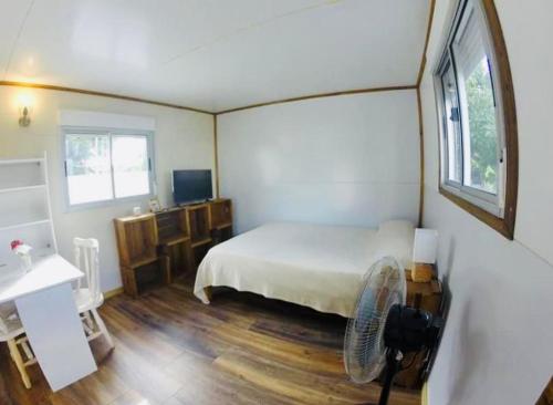 um quarto com uma cama branca e uma ventoinha em small house em Maldonado