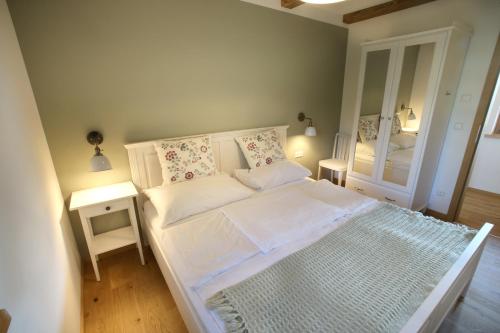 ein kleines Schlafzimmer mit einem weißen Bett und einem Spiegel in der Unterkunft Kellerstöckl Berg 79 in Strem